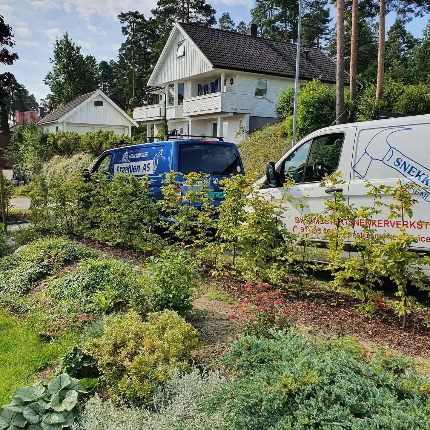 Blå og hvit varebil parkert ved hus.